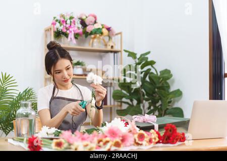 Flower Shop Konzept, Weibliche Floristin geschnitten Chrysantheme Stiele mit Schere für Blumensträuße zu machen. Stockfoto