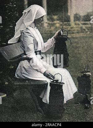 Lady Stradbroke, ehemals Helena Fraser und Ehefrau von George Rous, 3. Earl of Stradbroke, in Krankenschwester-Uniform im Familienhaus von Henham Hall in Suffolk abgebildet, in dem über die Bomben nachgedacht wird, die von deutschen Flugzeugen im April 1915 abgeworfen wurden. Das Haus wurde während des Ersten Weltkriegs in ein Militärkrankenhaus umgewandelt und erhielt Konvois von verwundeten Soldaten direkt aus Frankreich, die einst ausreichend gut an das Rote Kreuz weitergegeben wurden. Lady Stradbroke übernahm die alleinige Verantwortung als Oberschwester und überplante das Krankenhaus effizient. Henham Hall wurde 1953 abgerissen. Datum: 1915 Stockfoto