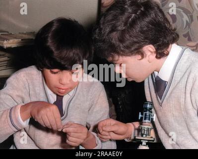 Zwei Schuljungen mit einem Mikroskop in einem Klassenlabor. Datum: Anfang 1970er Stockfoto