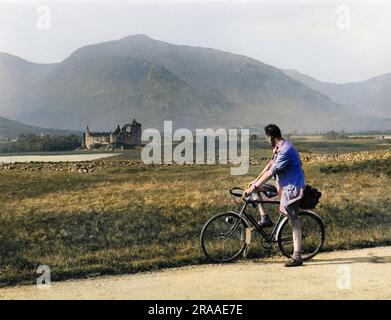 Ein Radfahrer bewundert die fernen Ruinen von Kilchurn Castle auf einer Insel auf Loch Awe. Erbaut im frühen 15. Jahrhundert; die Festung der Campbells von Breadalbane. Datum: 15. Jahrhundert Stockfoto