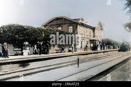 Eine Aussicht auf ein Bahnhofsgebäude und Passagiere auf der Plattform warten auf die nahende Dampfzug, in der Landschaft von Russland. Datum: Ende des 19. Jahrhunderts Stockfoto