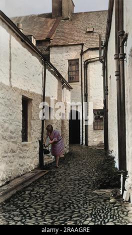 Eine Frau füllt einen Wasserkocher aus einem Wasserhahn in Newhaven, East Sussex. Datum: 1920er Stockfoto