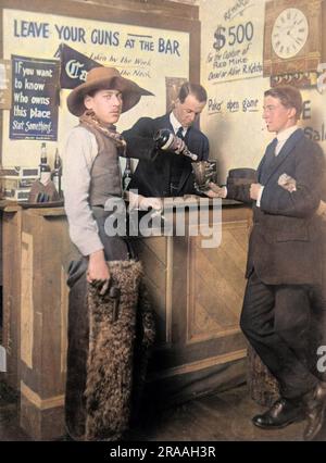 Ein Cowboy, der raucht und eine Waffe in der Bar hält. Auf dem Schild über der Bar steht: 'Lasst eure Waffen an der Bar liegen'. Stockfoto