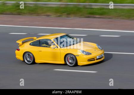 2000 Porsche 911 GT3 Yellow Car Coupe Benzin Gas 3600 cm3, alltäglicher, auf Rennstrecken ausgerichteter Supersportwagen mit 3,6-Liter-Flachsechsmotormotor „Mezger“; Fahrt mit hoher Geschwindigkeit auf der Autobahn M6 im Großraum Manchester, Großbritannien Stockfoto