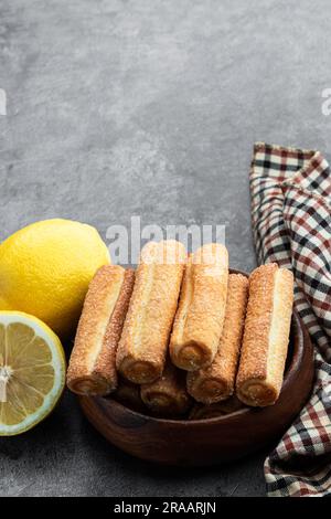 Hausgemachte Zitronenmarmelade mit Stäbchen in Holzschüssel auf grauem Hintergrund Stockfoto