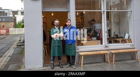 Zwei fröhliche, junge Cafe-Besitzer vor dem Coffee Shop lächelnd. Stockfoto