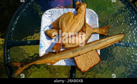 Räucherfisch auf einem Pappteller. Köstlicher hausgemachter Fisch. Zwei Schollen und ein Windfisch. Stockfoto