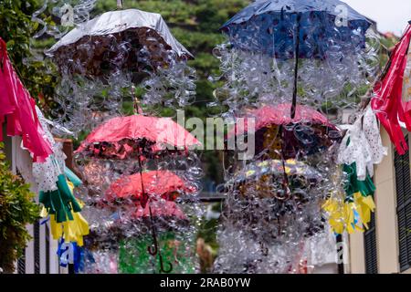 Kunstwerke aus Dutzenden von mehrfarbigen Regenschirmen, die über einer Straße in Camara de Lobos, Madeira, hängen. Stockfoto