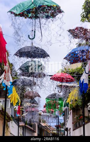 Kunstwerke aus Dutzenden von mehrfarbigen Regenschirmen, die über einer Straße in Camara de Lobos, Madeira, hängen. Stockfoto