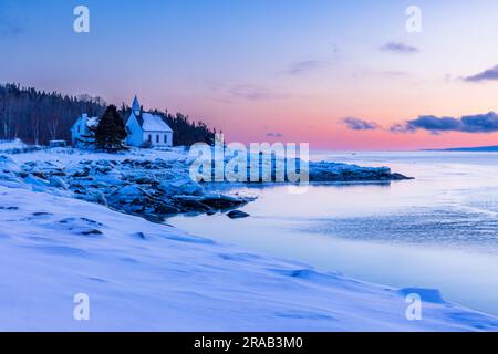 Charlevoix, Sonnenaufgang über der Kapelle von Port-au-Persil, typische Landschaft dieser Region zwischen Hügeln und Fluss. Stockfoto