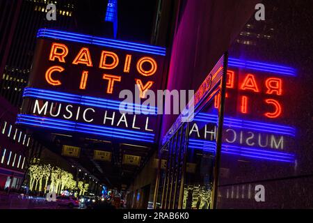 Das Neone-Schild der Radio City Music Hall spiegelt sich an der Wand des Rockefeller Center wider. Stockfoto