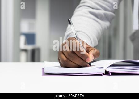 Nahaufnahme eines Mannes, der in ein Notizbuch schreibt Stockfoto