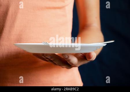 Dreckiger weißer Teller mit einer Gabel in der Hand eines Mädchens Stockfoto