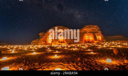 Sternenlicht über den antiken nabatäischen Gräbern der beleuchteten Stadt Hegra, Nachtpanorama, Al Ula, Saudi-Arabien Stockfoto