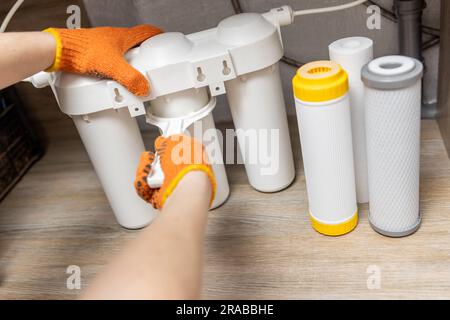 Der Installateur installiert oder wechselt den Wasserfilter. Ersatz-Aqua-Filter Stockfoto