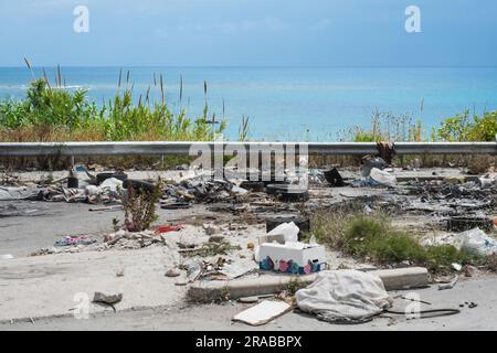 Spontane Müllhalde entlang der Straße mit Blick auf das Meer. Stockfoto