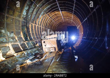 Ein alter verlassener U-Bahn-Tunnel mit rostiger Trolley-Lokomotive Stockfoto