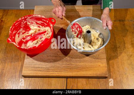 Eine weibliche Köchin überträgt Teig aus der Rührschüssel in die Pfanne, um irisches Soda-Brot zuzubereiten Stockfoto