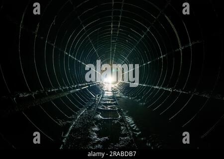 Dunkel dreckiger verlassener U-Bahn-Tunnel mit rostigen Eisenbahnen Stockfoto