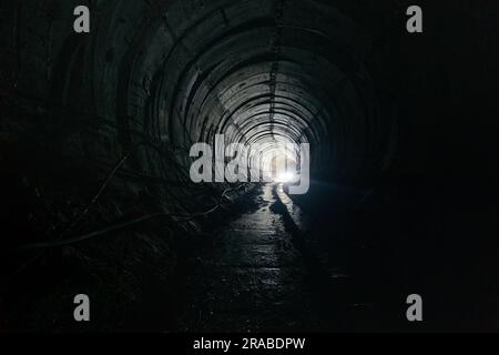 Dunkel dreckiger verlassener U-Bahn-Tunnel mit rostigen Eisenbahnen Stockfoto