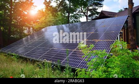 Photovoltaikpaneele stehen auf einer befestigten Fläche vor dem Hintergrund von Bäumen und Büschen. Solarmodule mit großer Oberfläche. Stockfoto