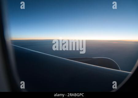 Blick durch das Flugzeugfenster am leeren Horizont bei Sonnenaufgang am klaren Morgen Stockfoto