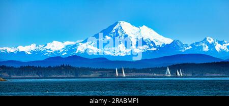 Tele-Nahaufnahme eines Segelboots vor einem schneebedeckten Mt. Baker, Cascade Range, Washington, USA Stockfoto