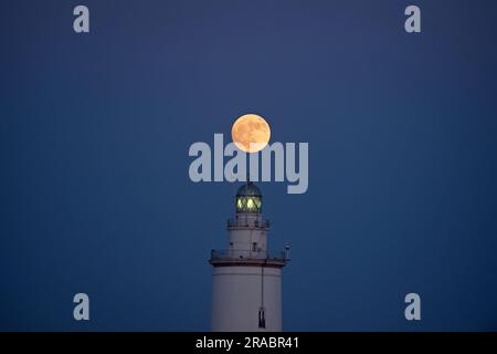 Malaga, Spanien. 2. Juli 2023. Der Buckmond, der am Himmel über einem Leuchtturm aufgeht, ist im Hafen von Malaga zu sehen. Anfang Juli findet der Vollmond der Hirsche als eines der beeindruckendsten astronomischen Ereignisse des Monats statt. Wenn der Vollmond stattfindet, erscheint er größer und heller als normal. (Credit Image: © Jesus Merida/SOPA Images via ZUMA Press Wire) NUR REDAKTIONELLE VERWENDUNG! Nicht für den kommerziellen GEBRAUCH! Stockfoto