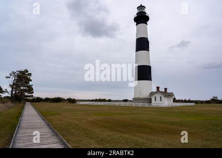 Blick auf den Woddded Path zum Horizont mit großem Leuchtturm an der Seite Stockfoto