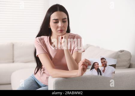 Verärgerte Frau, die zu Hause ein zerrissenes Foto hält. Scheidungskonzept Stockfoto
