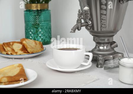 Klassischer Samovar, eine Tasse heißes Getränk und Snacks werden auf dem Tisch serviert. Traditionelle russische Teezeremonie Stockfoto