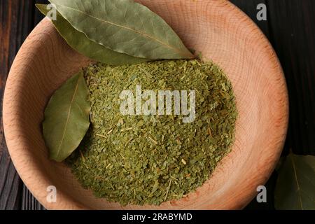 Ganze und gemahlene aromatische Lorbeerblätter in Holzschüssel, Draufsicht Stockfoto