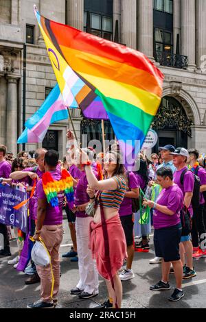 Teilnehmer der alljährlichen London Pride-Veranstaltung am 1. Juli 2023 auf Piccadilly in London march mit einer großen, bunten Flagge in Regenbogenfarben Stockfoto