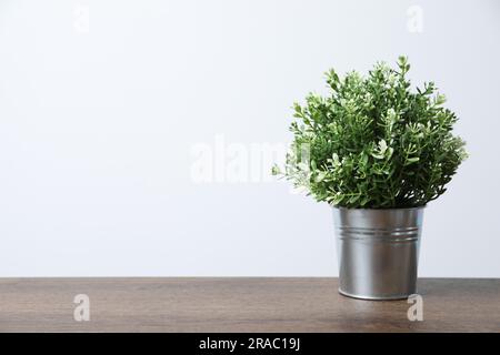 Künstlicher Topfthymian auf Holztisch vor weißem Hintergrund, Platz für Text Stockfoto