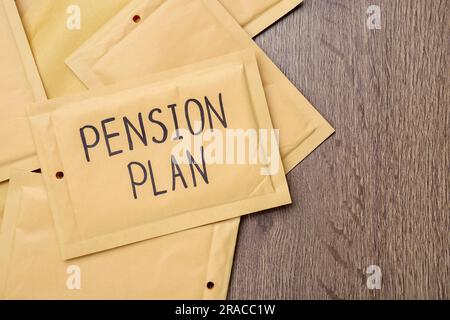Umschlag mit Worten Pensionsplan auf Holztisch, flach liegend. Platz für Text Stockfoto