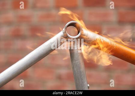 Manuelle Fahrradrenovierungsarbeiten, Lackentfernung mit einem Lötbrennerfeuer, um die Farbe eines Fahrradrahmens zu ändern. Nahaufnahme. Stockfoto