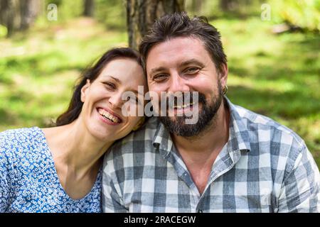 Porträt eines jungen Ehepaars, das an einem sonnigen Tag im Wald sitzt Stockfoto
