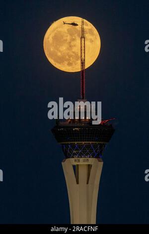 Las Vegas, Nevada, USA. 2. Juli 2023. Ein Hubschrauber fliegt vor Vollmond, während er am 2. Juli 2023 in Las Vegas, Nevada, über dem Strat Hotel and Casino aufsteigt. Der sogenannte Full Buck Moon, der näher an der Erde kreist als viele der anderen Full Moons dieses Jahr, macht einen der vier Supermonde von 2023 aus. (Kreditbild: © David Becker/ZUMA Press Wire) NUR REDAKTIONELLE VERWENDUNG! Nicht für den kommerziellen GEBRAUCH! Stockfoto