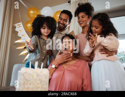 Geburtstag, Überraschung und Kinder mit Großmutter mit Kuchen für Veranstaltungen, Partyfeiern und gesellschaftliche Zusammenkünfte. Glückliche Familie, feiern und aufgeregt Stockfoto