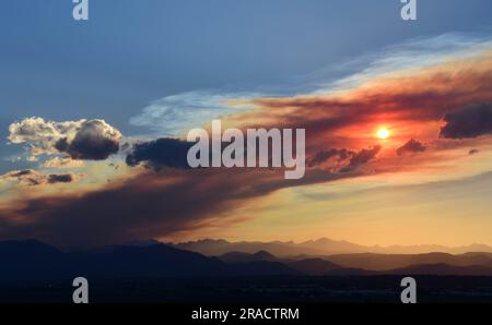 Farbenfroher Sonnenuntergang über der vorderen Ranch der felsigen Berge durch den rauchigen Dunst des Quellbachs, Wildfeuer in der Nähe des Fallschirms, aus der Sicht des Besen Stockfoto