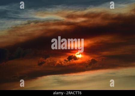 Farbenfroher Sonnenuntergang über der vorderen Ranch der felsigen Berge durch den rauchigen Dunst des Quellbachs, Wildfeuer in der Nähe des Fallschirms, aus der Sicht des Besen Stockfoto