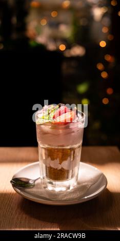 Erdbeertiramisu-Dessert auf dunklem Hintergrund mit verschwommenen Lichtern Stockfoto