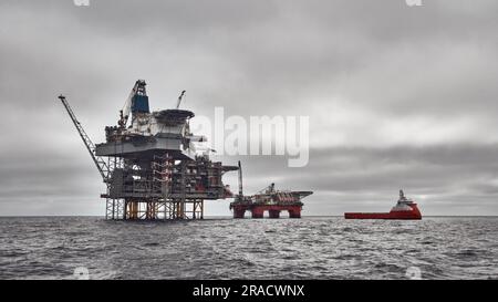 Panoramablick auf die Bohrinsel Jack Up, die halbtauchfähige Plattform und das Versorgungsschiff an einem dunklen bewölkten Tag im Meer. Nordsee-Öl und -Gas. Stockfoto