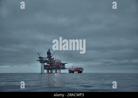 Panoramablick auf die Öl- und Gasplattform, Hebebühne im Meer in der Dämmerung mit dunklem Himmel und klarer Wasseroberfläche in der Nordsee. Stockfoto