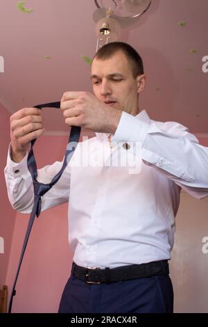 Ein Mann mit einer Krawatte, um ein weißes Hemd anzuziehen Stockfoto