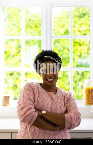 Porträt einer glücklichen, übergroßen afroamerikanischen Frau am Fenster in der Küche Stockfoto