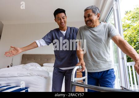 Glücklicher, vielseitiger männlicher Arzt und älterer männlicher Patient, der zu Hause Krücken benutzt. Medizinische Dienstleistungen, Check-up, Hausbesuch, Gesundheit, Wohlbefinden und s Stockfoto