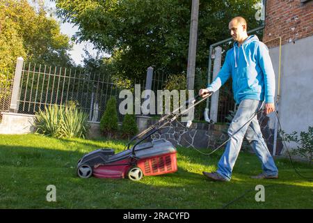 Der Mann mäht Gras in seinem eigenen Garten Stockfoto