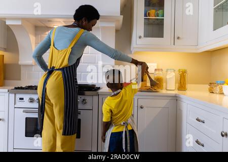 Rückansicht von afroamerikanischer Mutter und Sohn beim Kochen von Pfannkuchen in der Küche Stockfoto