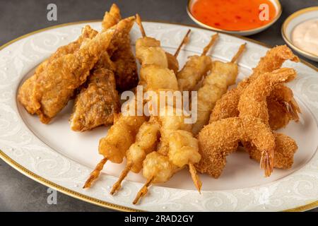 Meeresfrüchte-Tempura mit Fisch und Garnelen auf einem Tisch aus schwarzem Stein Stockfoto